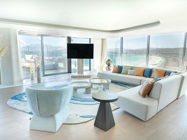 A modern living room with a large sofa, a coffee table, and a TV.