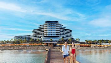 Un hôtel moderne doté d’un bâtiment aux lignes courbes, d’une jetée en bois et bordant un plan d’eau paisible.