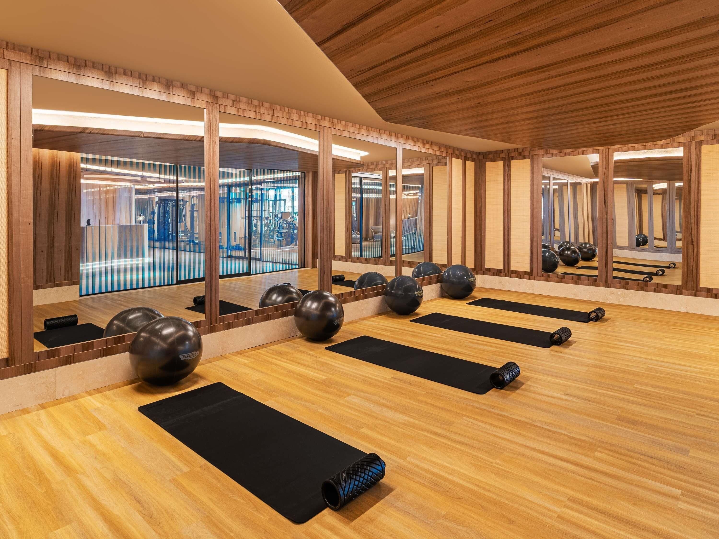 A gym with exercise mats, black exercise balls, and a mirrored wall.
