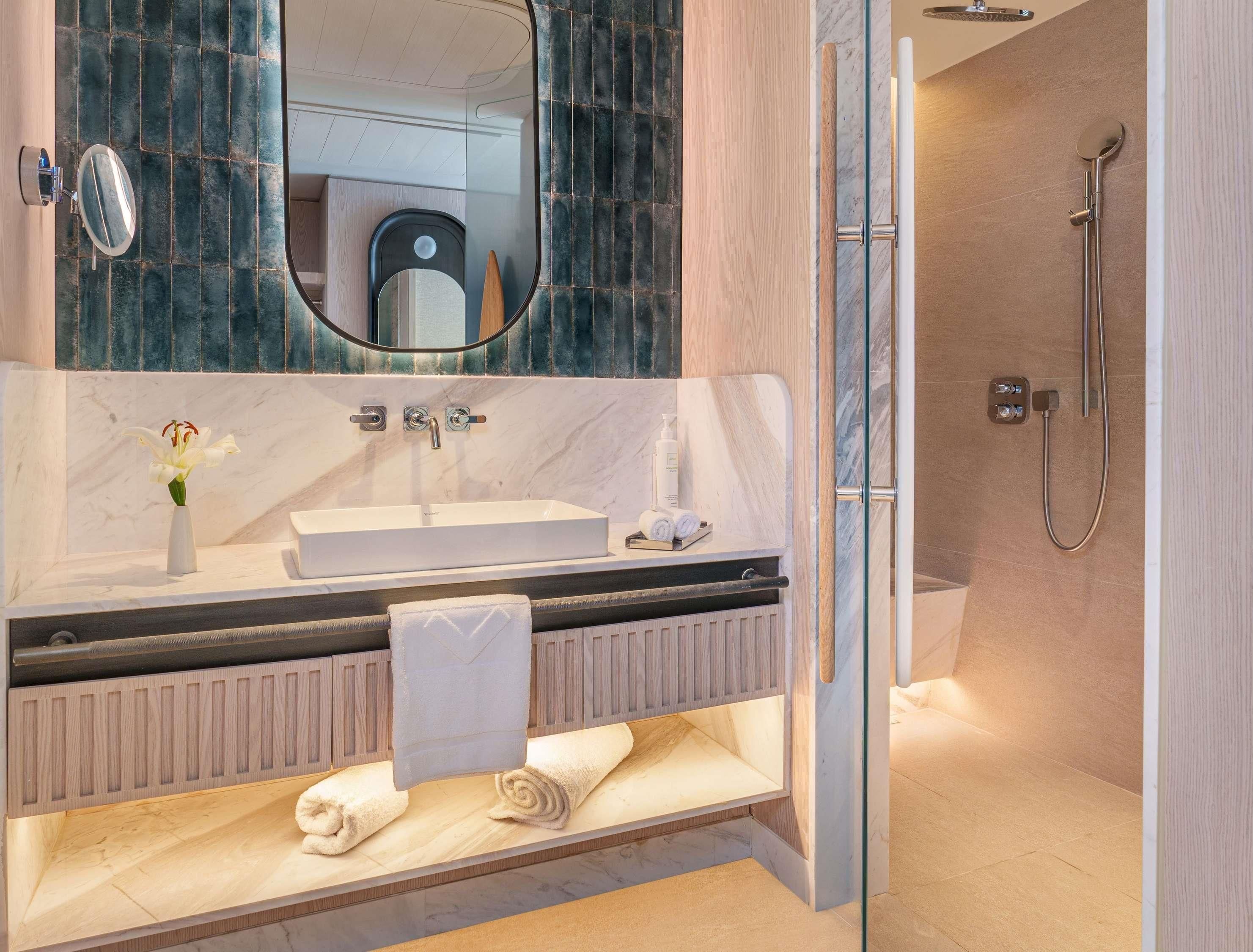 A modern bathroom with a marble vanity, a glass shower enclosure, and a built-in toilet.