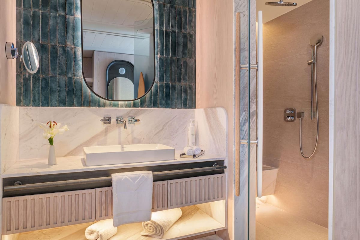 A modern bathroom with a marble vanity, a glass shower enclosure, and a built-in toilet.