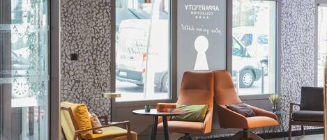 Un interior moderno con un ventanal grande, una zona de estar con dos sillones, una mesita y un cartel decorativo en la pared.