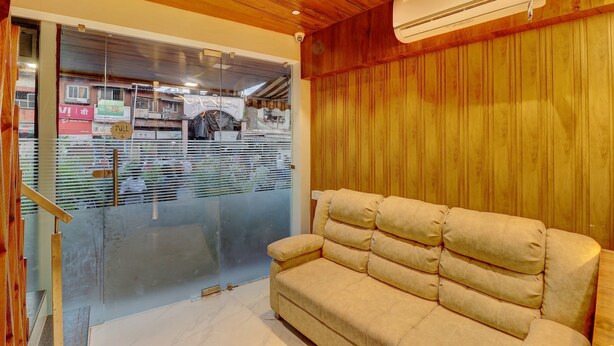 A room with a beige sofa, wooden ceiling, and a glass door leading outside. - Hotel Amber Suite (Mumbai)
