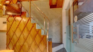 A modern interior with a wooden wall, a glass staircase, and a door with a frosted glass panel. - Hotel Amber Suite (Mumbai)