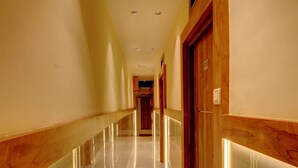 A long, polished hallway with wooden doors and a marble floor. - Hotel Amber Suite (Mumbai)