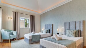 A modern hotel room with two beds, a seating area, and a window with curtains. - Villa Gasparini (Funchal)
