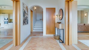 A spacious hallway with tiled flooring, wooden doors, and a staircase leading to another level. - Villa Gasparini (Funchal)
