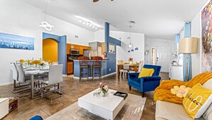 Een moderne woonkamer met een eethoek, keuken en een blauwe accentmuur.