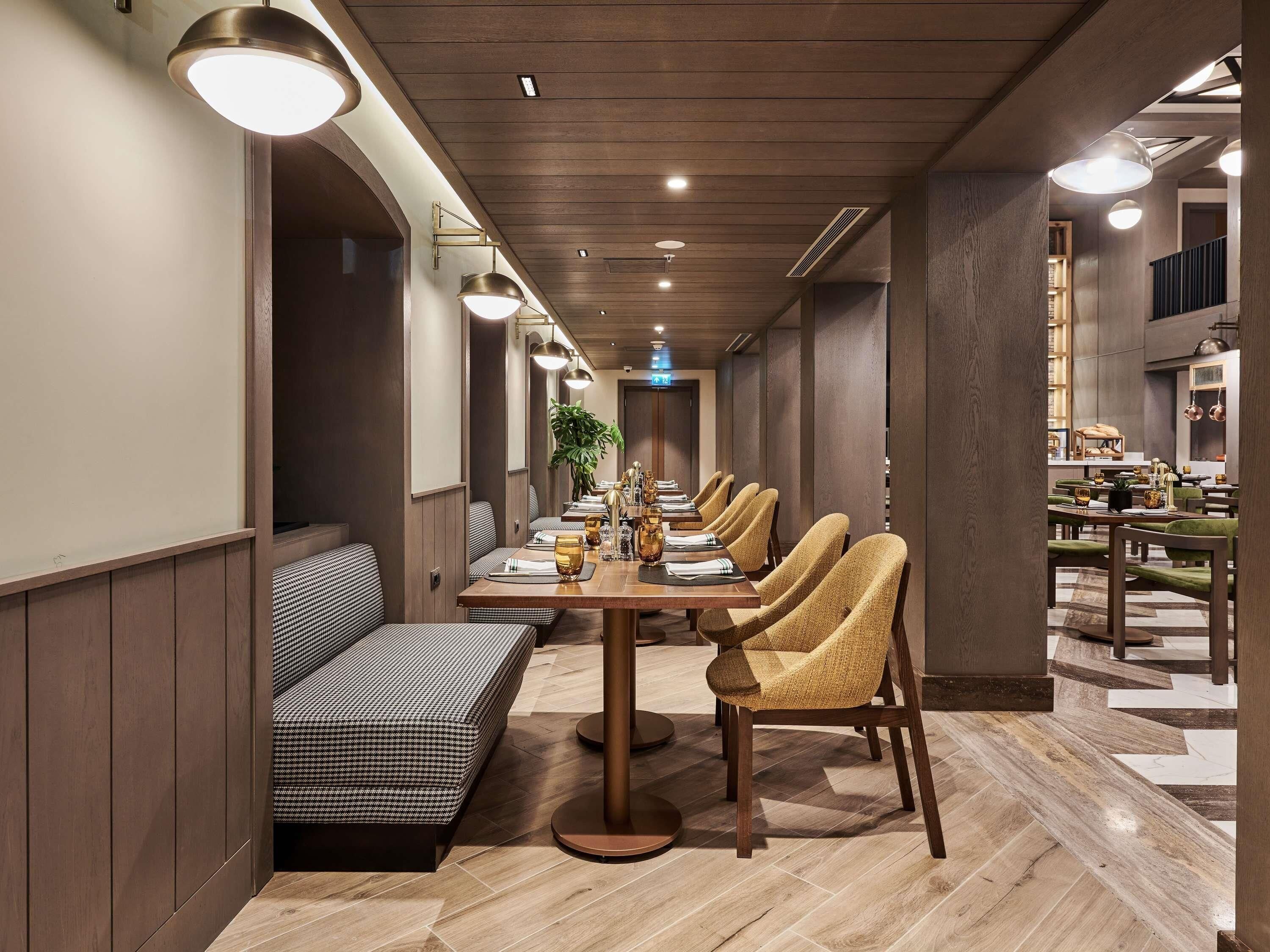 A long dining table with chairs, benches, and a potted plant in a modern interior.