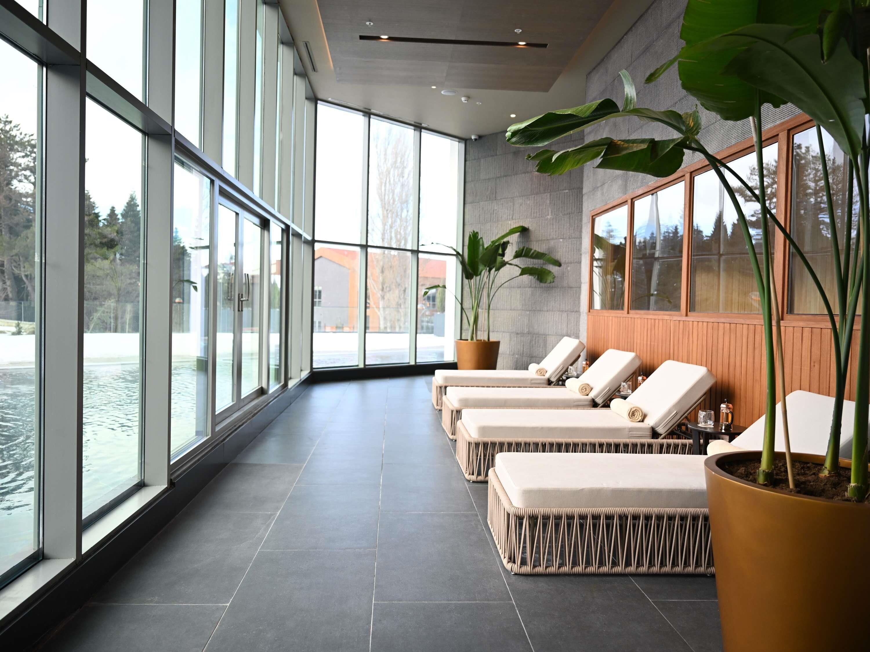 Uma área de spa com grandes janelas, espreguiçadeiras e plantas em vasos.