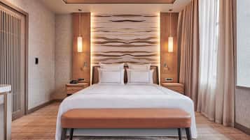 Una habitación de hotel con una cama grande, mesitas de noche, un banco y una pared con diseño.