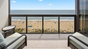 Un balcón con vistas a la playa, que incluye una zona de estar con dos sillas y una mesita.