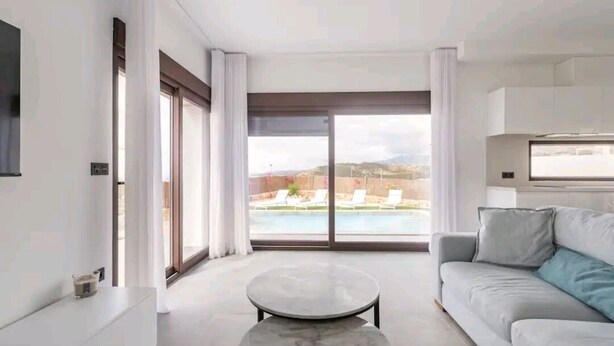 A modern living room with a large window, a sofa, a coffee table, and a flat-screen TV. - Villa with sea view (Finestrat)