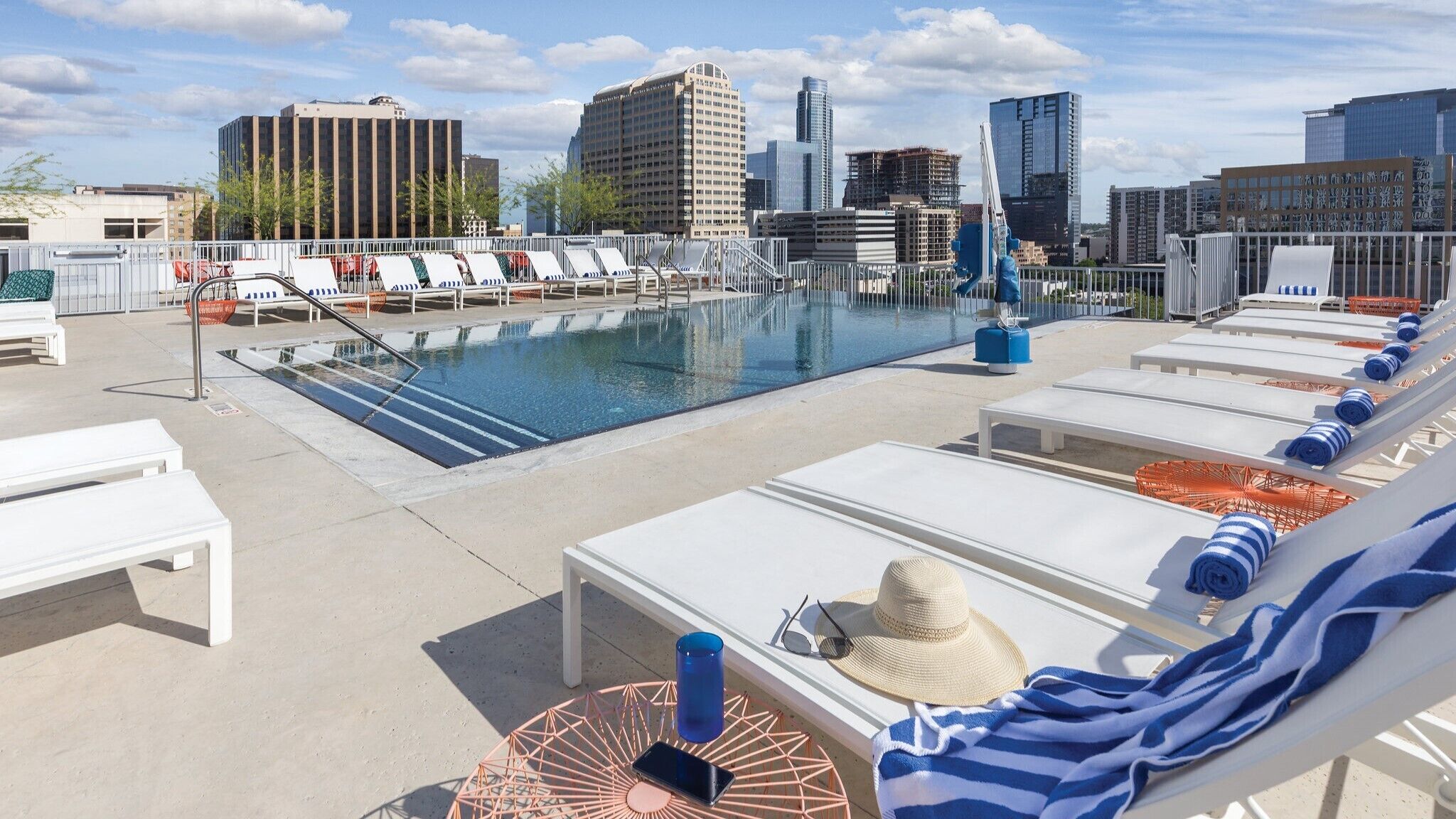 A rooftop pool with lounge chairs and a cityscape view.