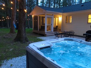 Een bubbelbad in een achtertuin met een overdekt terras en een afgesloten ruimte.