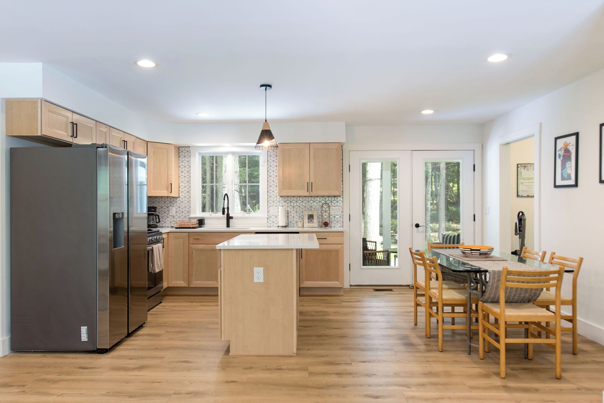 A modern kitchen with wooden cabinets, a stainless steel refrigerator, and a central island.