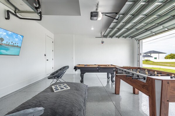 A modern indoor space with a pool table, foosball table, and a comfortable seating area.