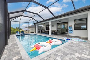 A swimming pool with inflatable swan floats, a covered patio area, and a view of the surrounding landscape.