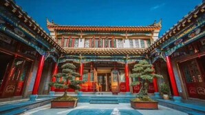 Ein traditionelles chinesisches Gebäude mit aufwendiger Architektur, einem zentralen Eingang und symmetrischer Gestaltung.