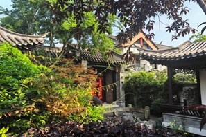 A traditional Chinese garden with a pavilion, stone bridge, and lush vegetation. - Taohuayuan Liu Contract Chun Inn (Taoyuan)