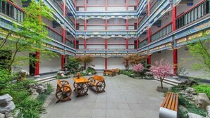 Ein mehrgeschossiges Atrium mit Innenhof, ausgestattet mit traditionellem Holzmöbel und Steinelementen.