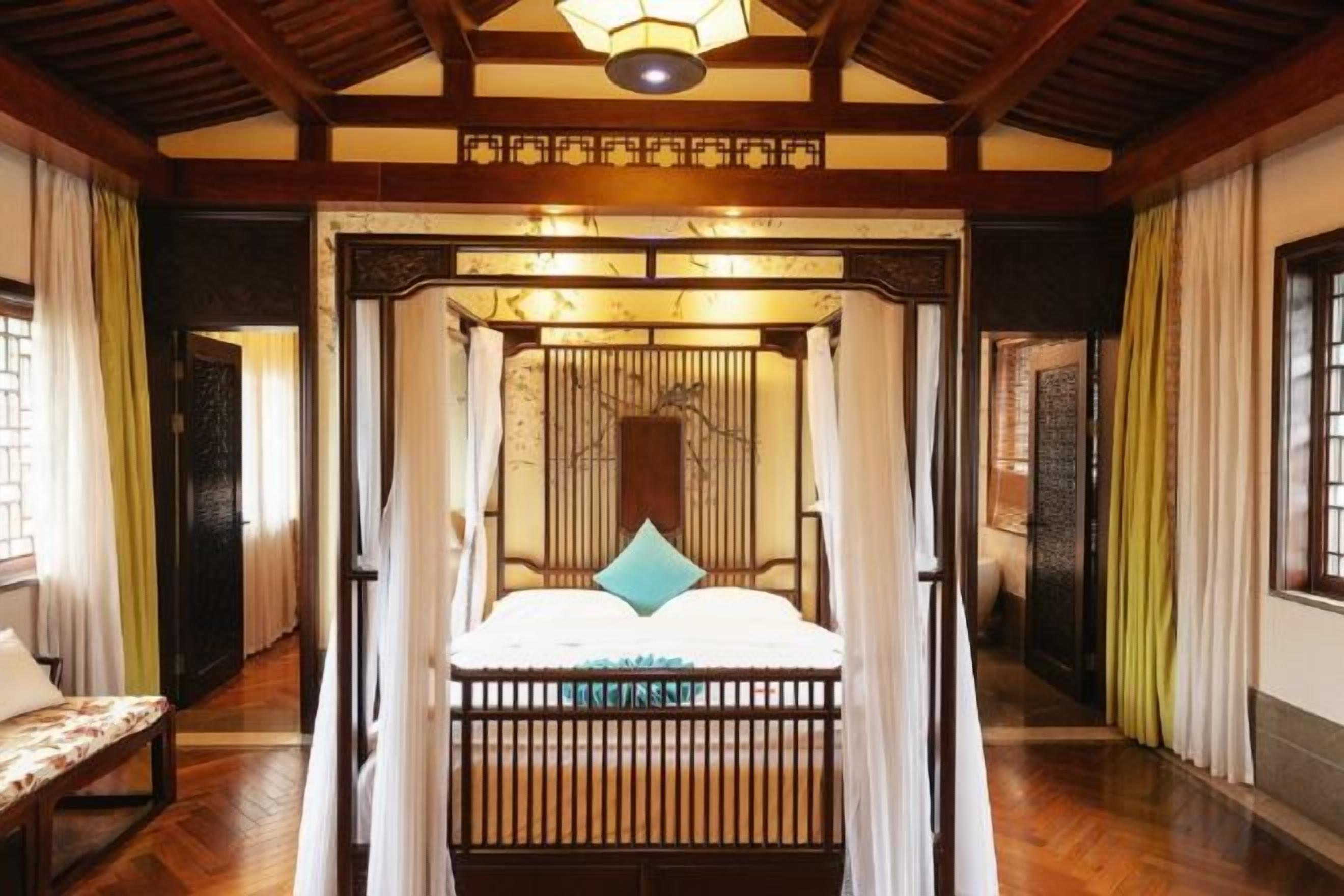 Une chambre de style traditionnel, dotée d’un lit à baldaquin, de parquet et d’un plafond avec des poutres apparentes.