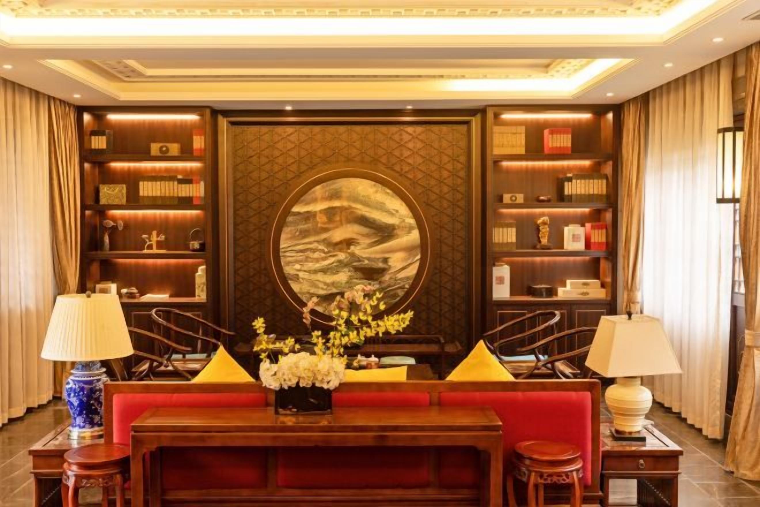 Un hall con un sofá rojo, una mesa de centro de madera y una gran obra de arte circular en la pared.