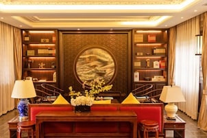 Un hall con un sofá rojo, una mesa de centro de madera y una gran obra de arte circular en la pared.