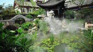 Ein traditioneller chinesischer Garten mit Steinbrücke, Wasserfall und Teich mit Seerosen.