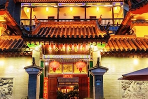 A traditional Chinese building with a tiled roof, ornate decorations, and a sign with Chinese characters.