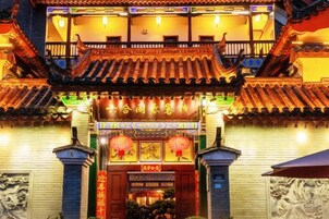 A traditional Chinese building with a tiled roof, ornate decorations, and a sign with Chinese characters.