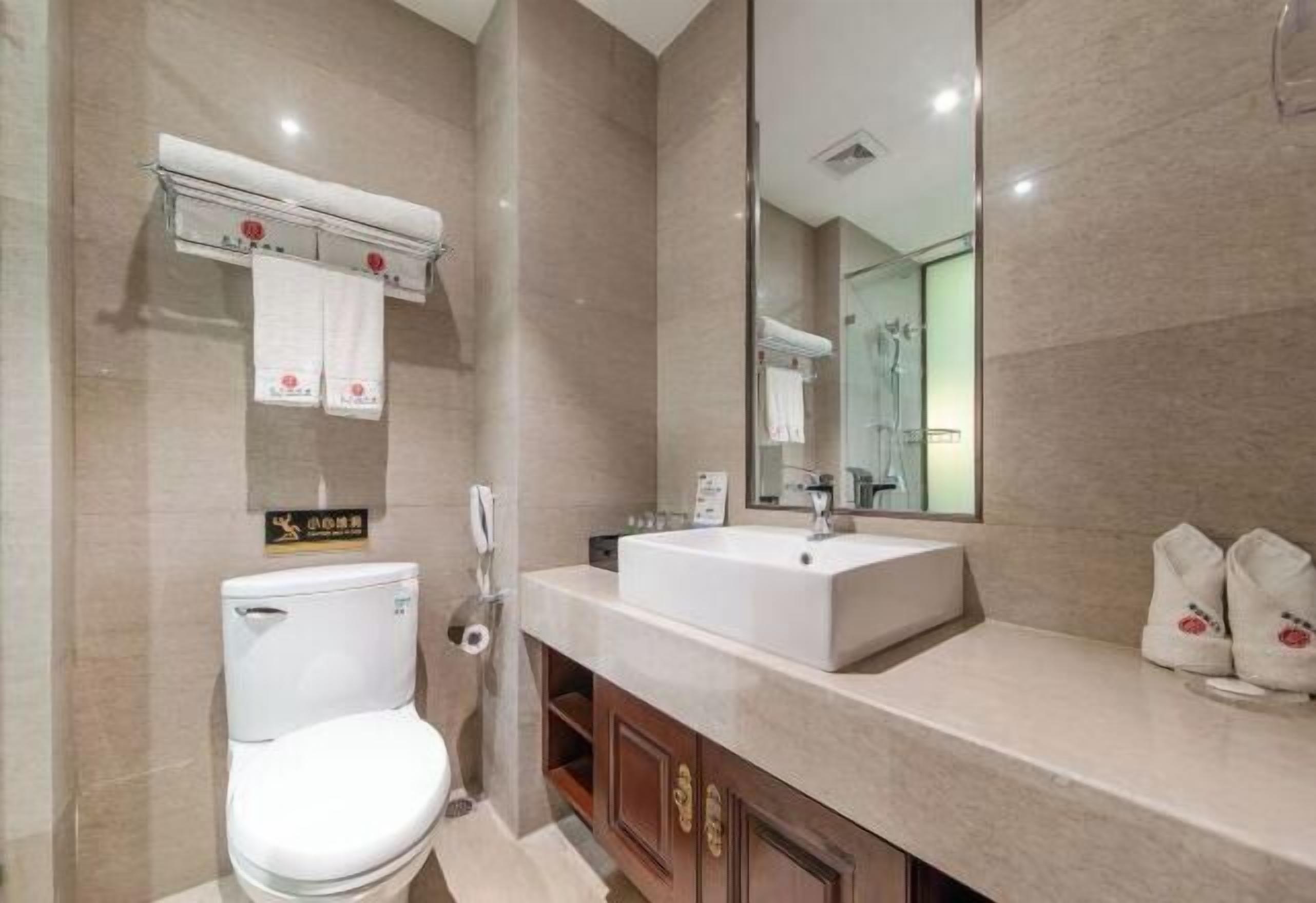 Un baño moderno con inodoro, lavamanos y espejo.