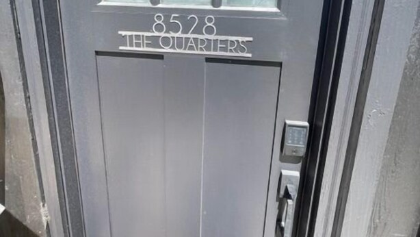 A dark grey door with the number 8528 and the words "THE QUARTERS" above it.