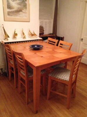 A dining area with a rectangular table and six chairs, featuring a bowl on the table and a framed picture on the wall.