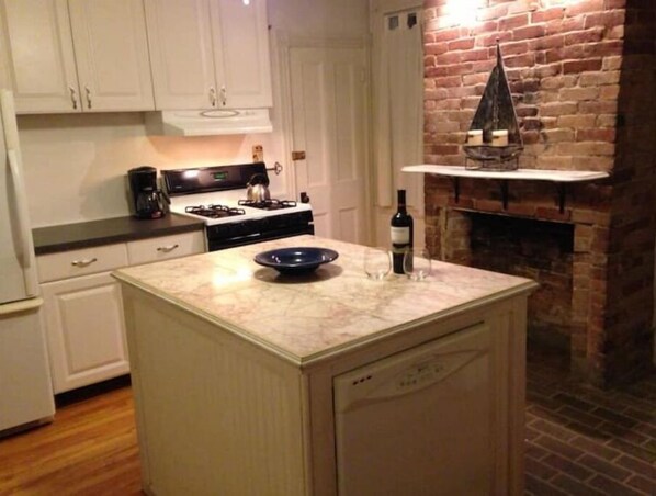 Enjoy cooking and socializing in this kitchen with a central island, stove, and kettle, perfect for a warm and inviting atmosphere.