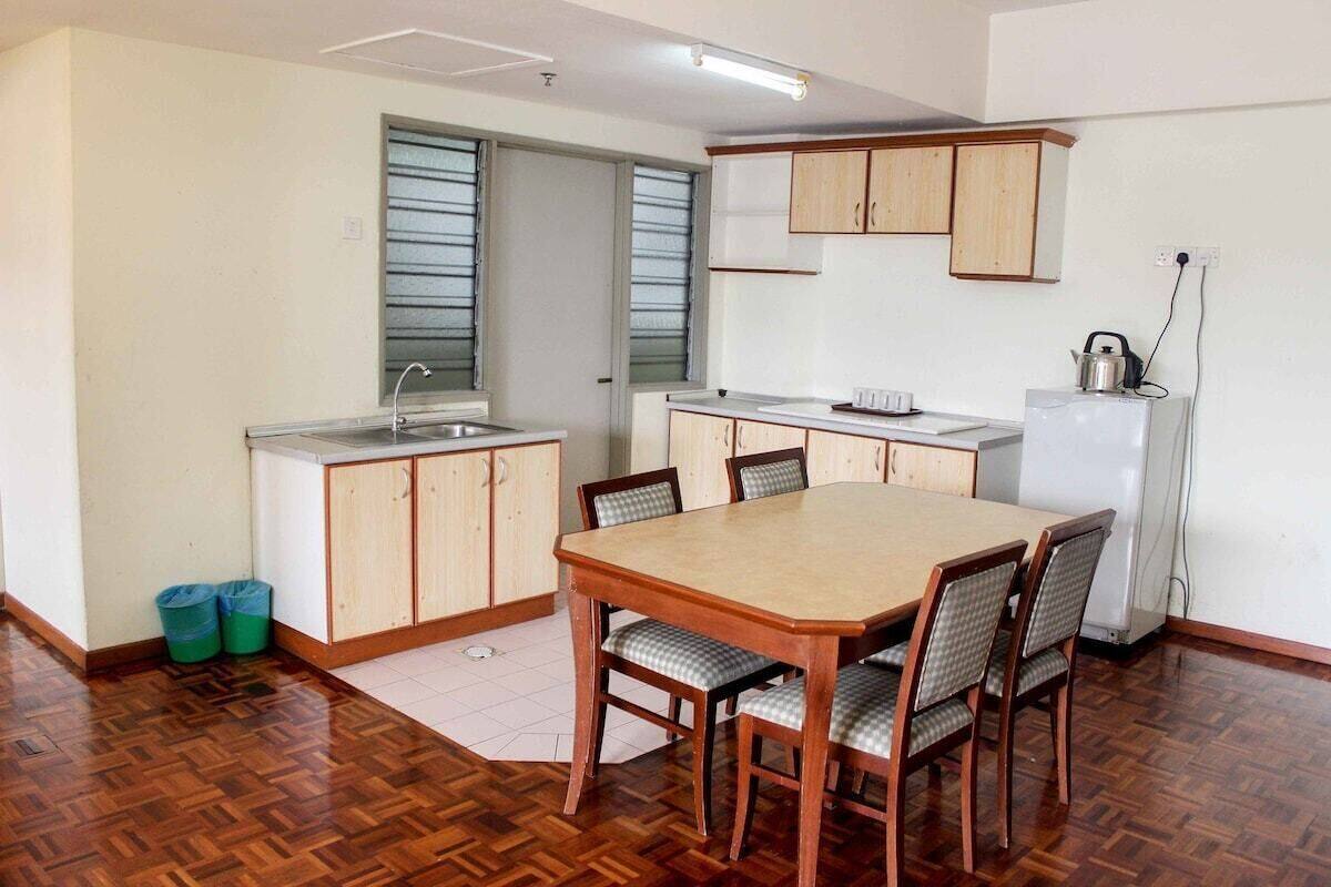 A compact kitchen with a dining table, chairs, and a refrigerator.