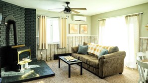A cozy living room with a fireplace, a ceiling fan, and a comfortable couch. - Winter Vacation Chalet at Powderhorn Mountain (Ironwood Township)