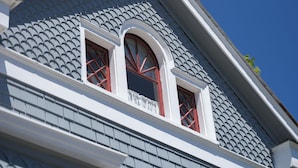A building with a grey shingled roof, white trim, and two red-framed windows. - Blocks from Ocean - KING BEDROOM SUITE (PACIFIC GROVE)