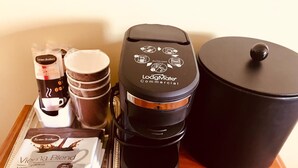A coffee maker, a coffee pod, a cup, and a container on a wooden table.