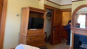 A room with a wooden dresser, a television, a door with a number, and a mirror.