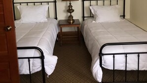 Una habitación con dos camas individuales, una mesita de noche con lámpara y dos cuadros en la pared.