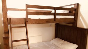 A bunk bed with a wooden frame and white bedding. - Queen Bed with Bunk bed (PACIFIC GROVE)