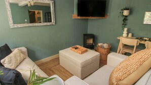 Een woonkamer met een bank, een voetenbankje en een aan de muur bevestigde televisie.