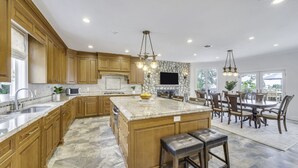 Une cuisine spacieuse dotée de meubles en bois, d’un grand îlot central et d’un coin repas avec une table et des chaises.