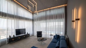 Een moderne woonkamer met een grote bank, een televisie en een eettafel.