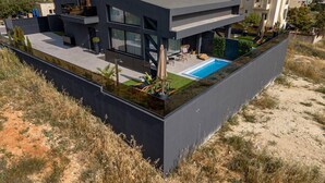 Een modern huis met twee verdiepingen, een zwembad op het dak, grote ramen en een plat dak.