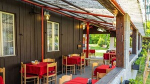 Un área de comedor al aire libre con mesas y sillas de madera, cubierta por una estructura de techo.