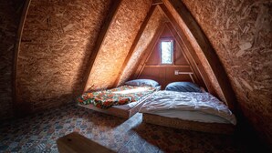 Un pequeño dormitorio en el ático con techo inclinado, una ventana y una alfombra estampada.