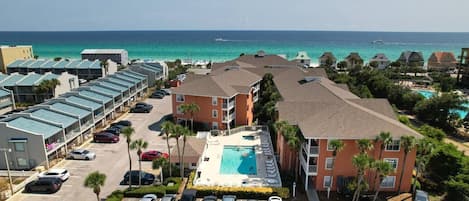 A hotel with a pool, parking lot, and ocean view.
