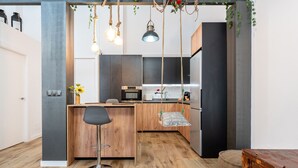 Een moderne keuken met een centraal eiland, houten vloeren en hangende lampen.
